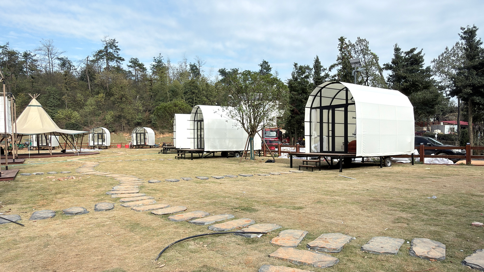 Luxury glamping cabin tents with white fabric cover and glass doors installed at outdoor campsite