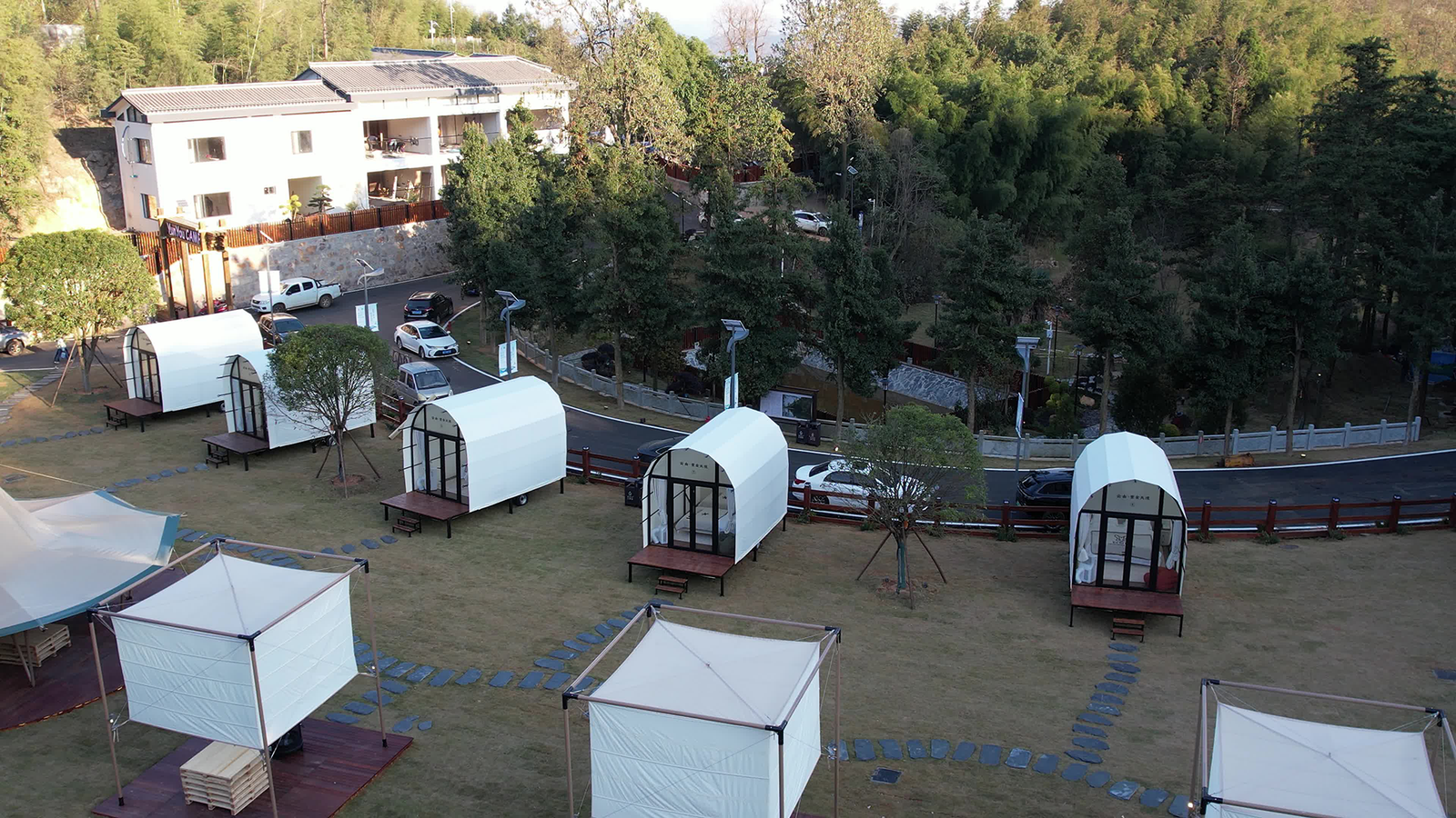 High angle view of outdoor glamping resort with luxury cabin tents and square canopy gazebos
