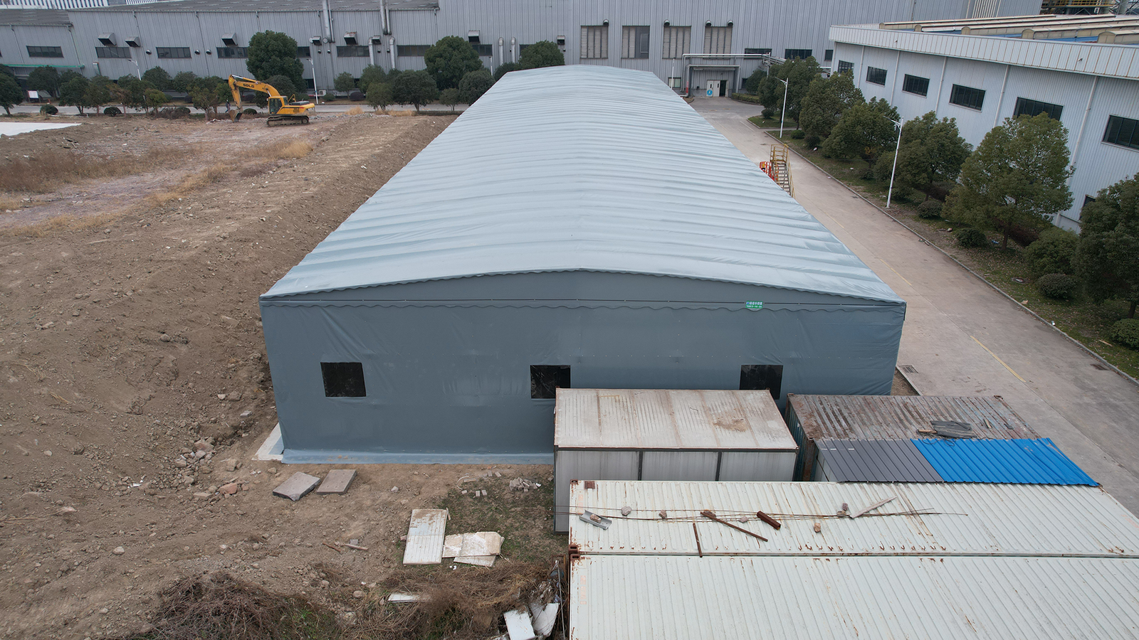 Front high-angle view of a large grey modular temporary storage tent in an industrial area