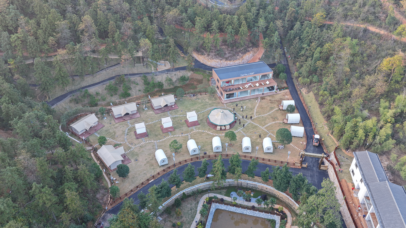 Aerial view of a luxury glamping resort surrounded by forest with geodesic dome tents and safari tents