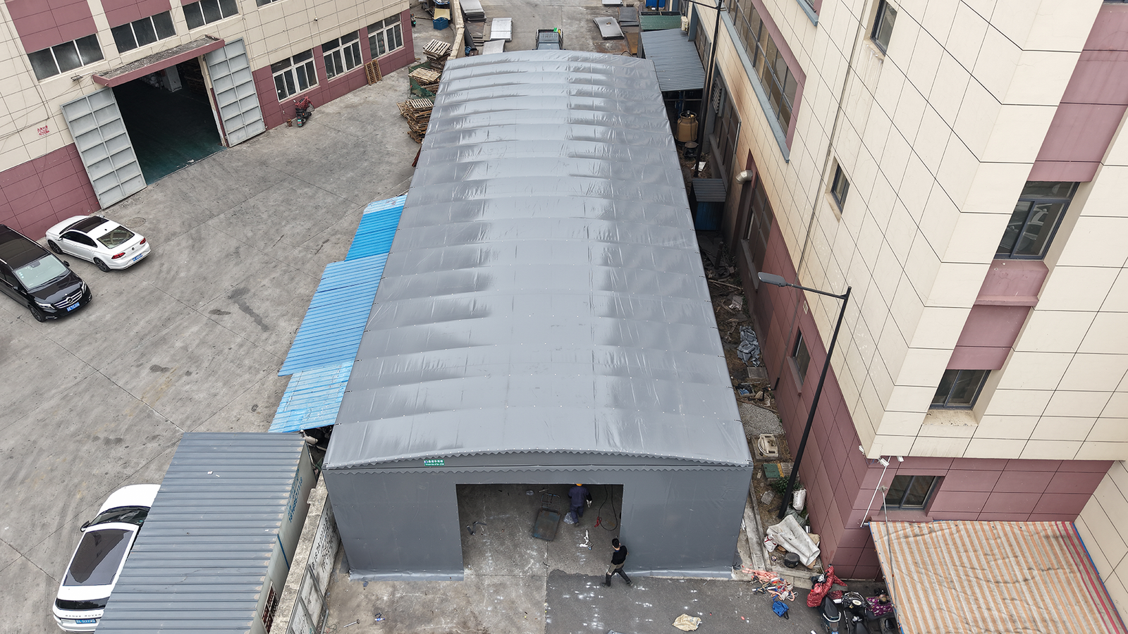 High angle view of a grey heavy duty motorized retractable warehouse canopy in a factory yard