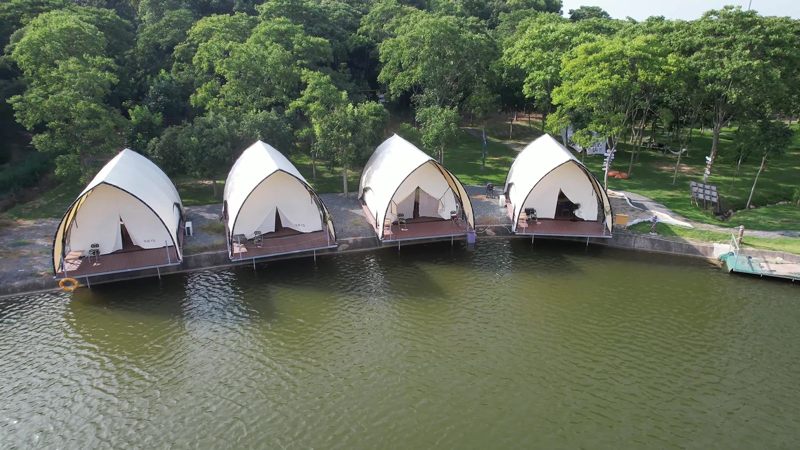 Luxury lakeside glamping tents with wooden platforms and steel frame structure in nature resort